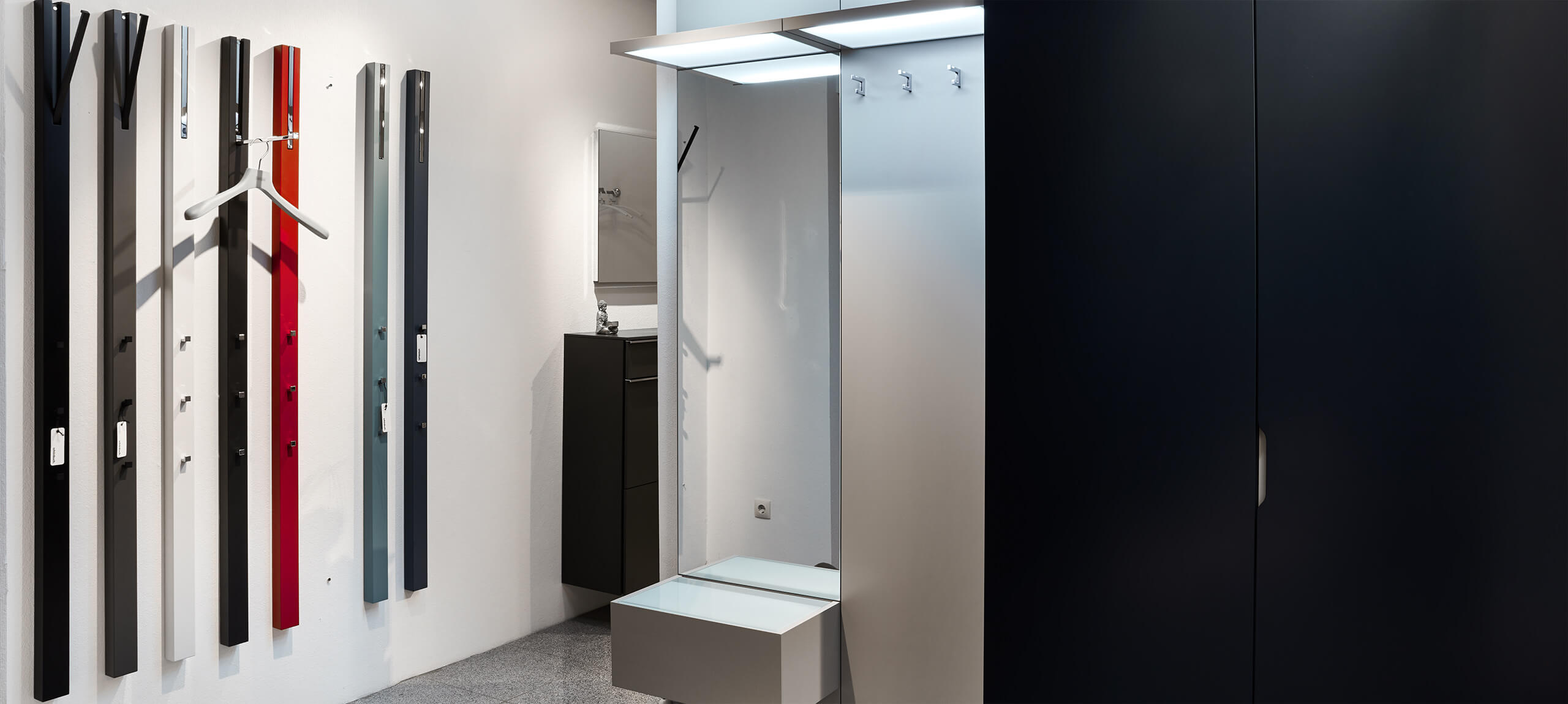 Eingansbereich mit weißer Garderobe, Beleuchtung und Sitzgelegenheit