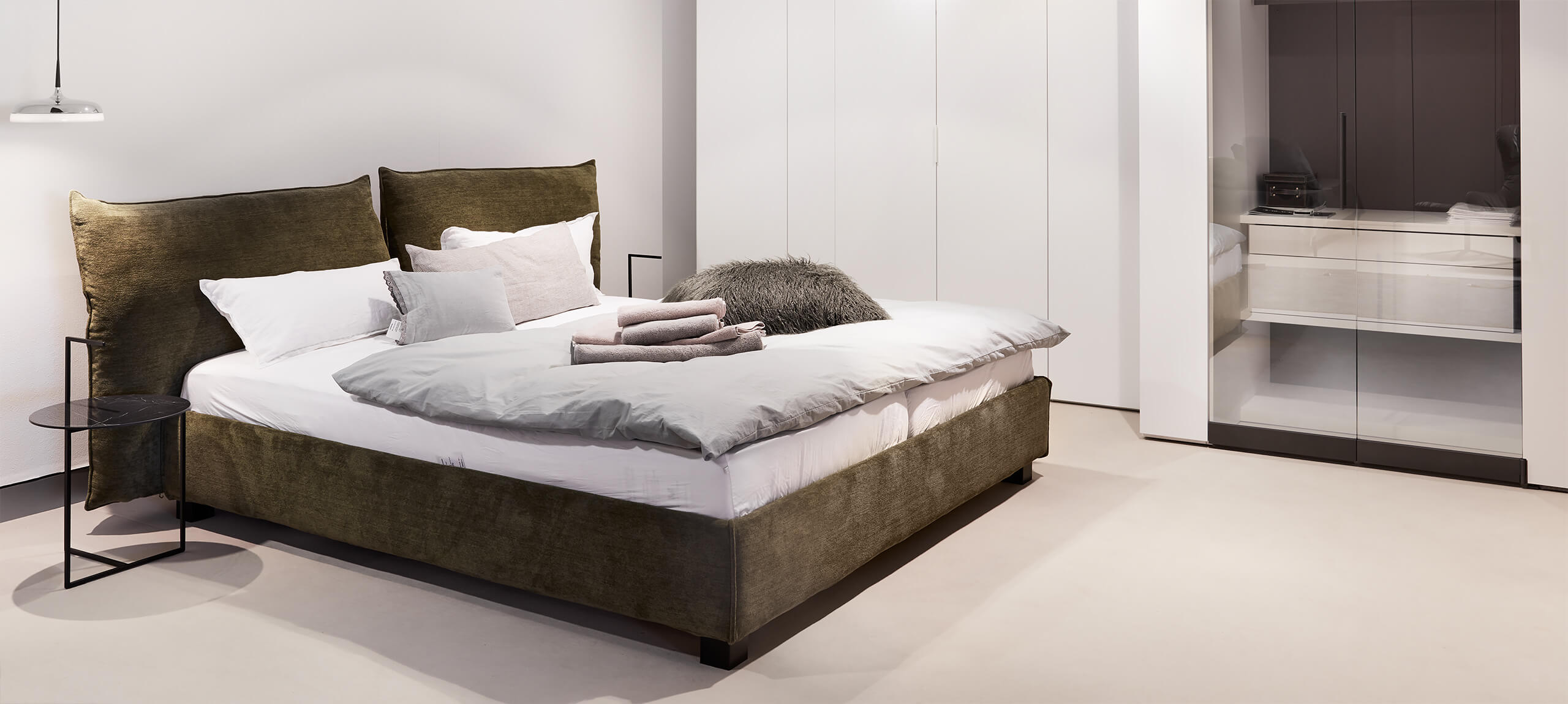 Schlichtes Schlafzimmer mit grünem Boxspringbett