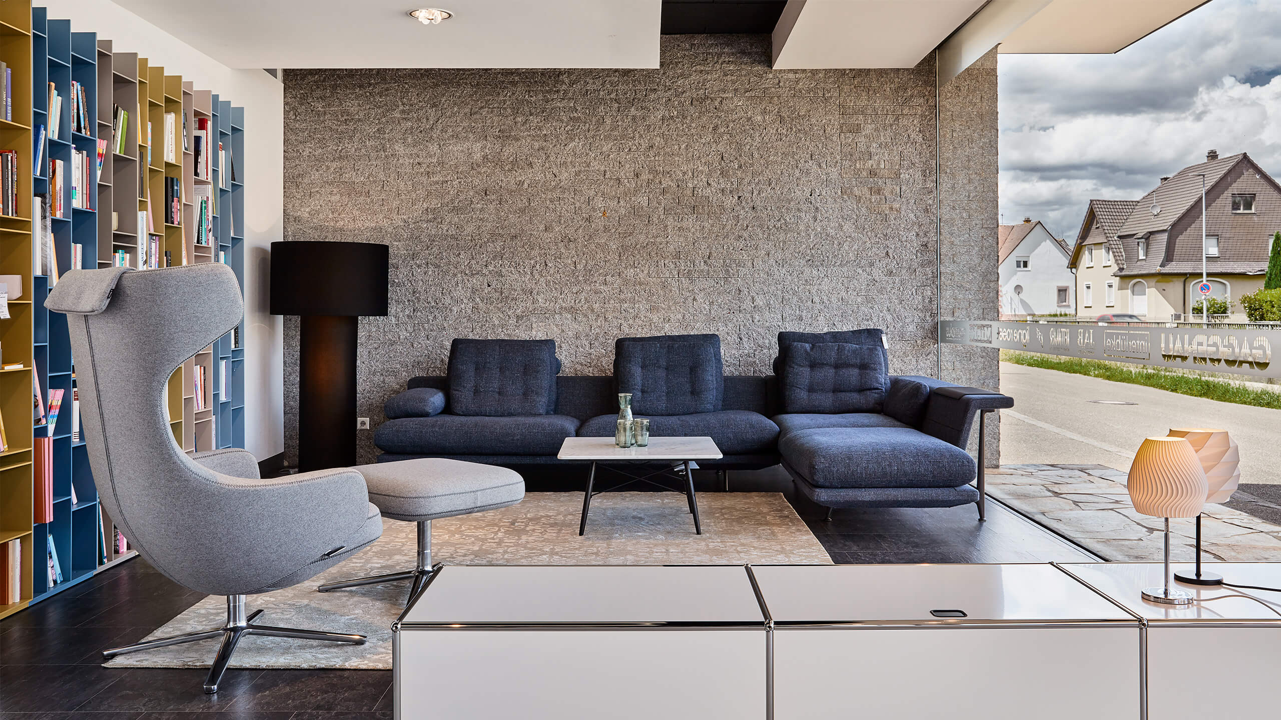 blaue Sitzecke mit Beistelltisch, grauer Sessel mit Fußablage - Wohnen, Wohnzimmer, Sofa, Wohnlandschaft, Beistelltisch, Wohnzimmertisch, Teppich, Accessoires - bühler einrichtungen in Friesenheim bei Offenburg zwischen Karlsruhe und Freiburg